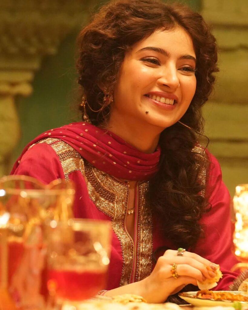 Sara Arjun wearing a rose pink embroidered kurta with matching dupatta and sharara, styled in a traditional indoor setting with warm lighting.