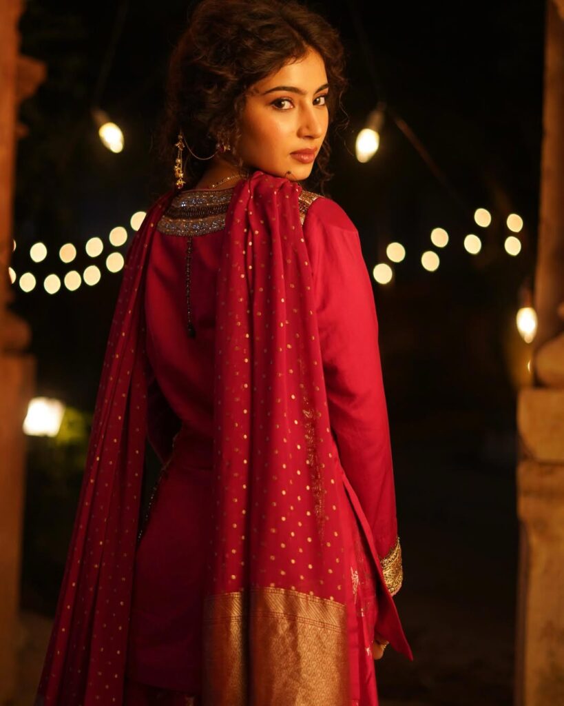 Sara Arjun wearing a rose pink embroidered kurta with matching dupatta and sharara, styled in a traditional indoor setting with warm lighting.